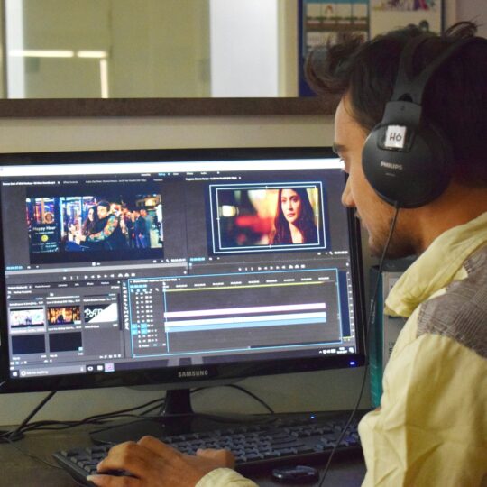 a man sitting in front of a computer with headphones on