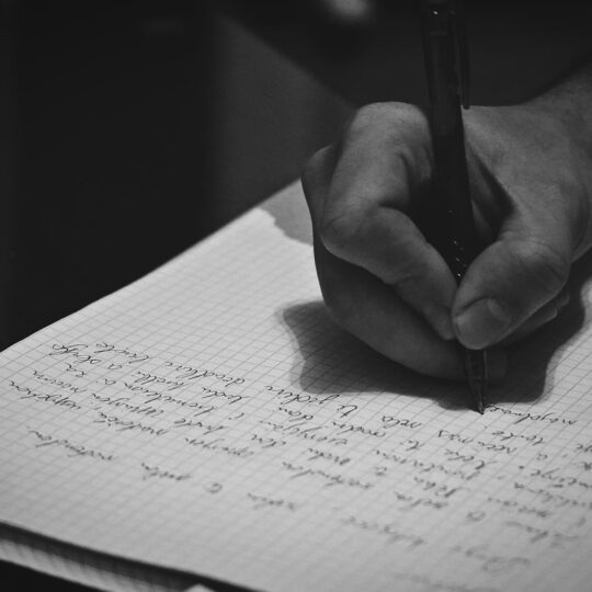 A person writing on a notebook with a pen
