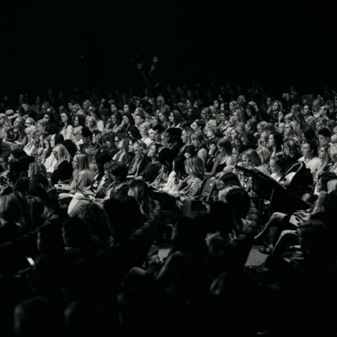 An audience watches a performance in a dark theater