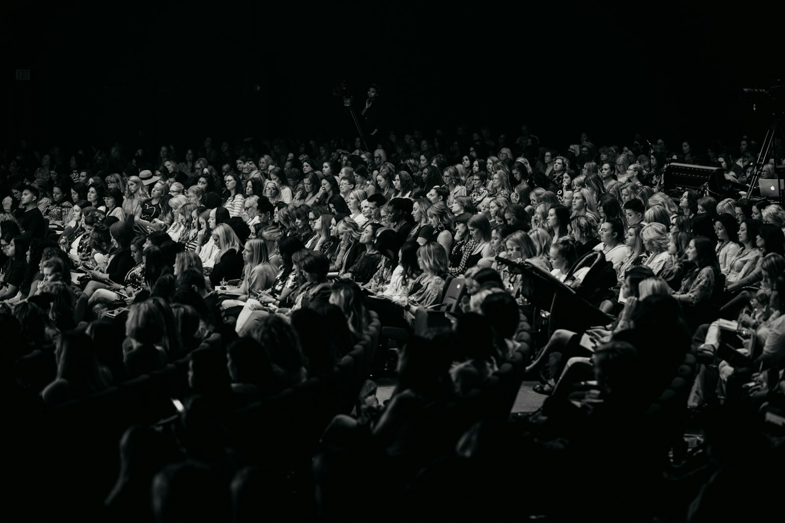 An audience watches a performance in a dark theater