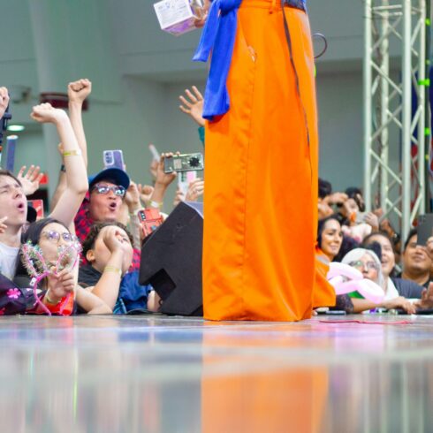 Crowd cheers for a person in orange costume