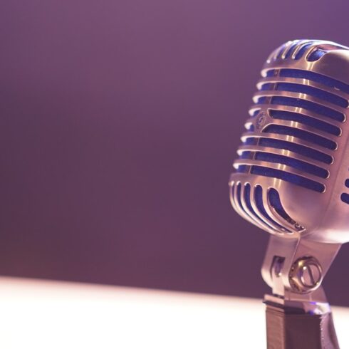 게임 캐릭터 목소리의 힘, 한 명의 성우가 만든 생명력 A vintage silver microphone with blue accents against a soft purple background