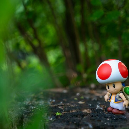 Toad figurine with backpack on tree stump in forest