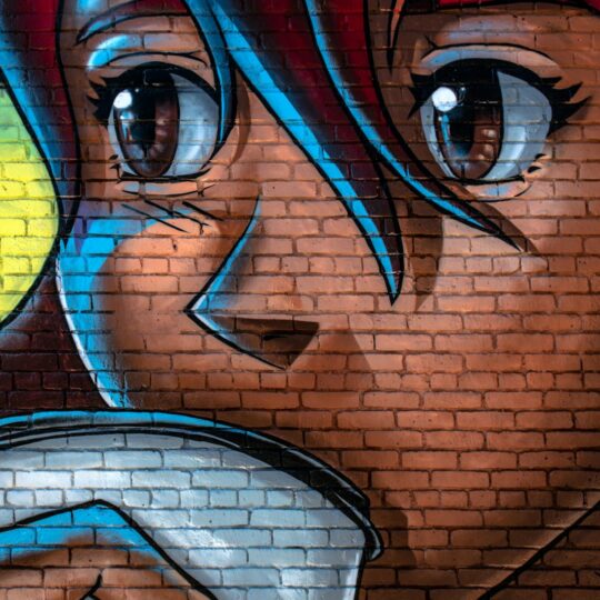 Anime style mural of a face painted on a red brick wall